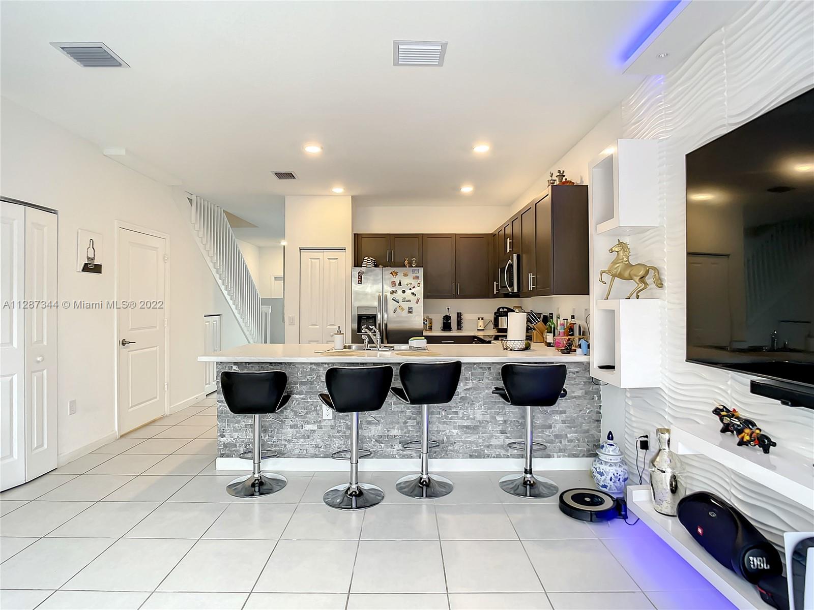 18272 Southwest 148th Road, Unit 18272 Miami, FL 33187 - Photo 8 of 19 a kitchen with a dining table chairs and a view of living room