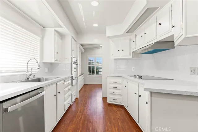 a kitchen with stainless steel appliances white cabinets sink and wooden floor