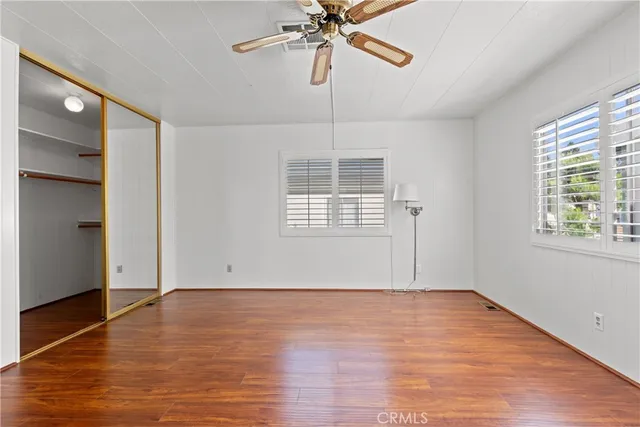 a view of an empty room with window and wooden floor