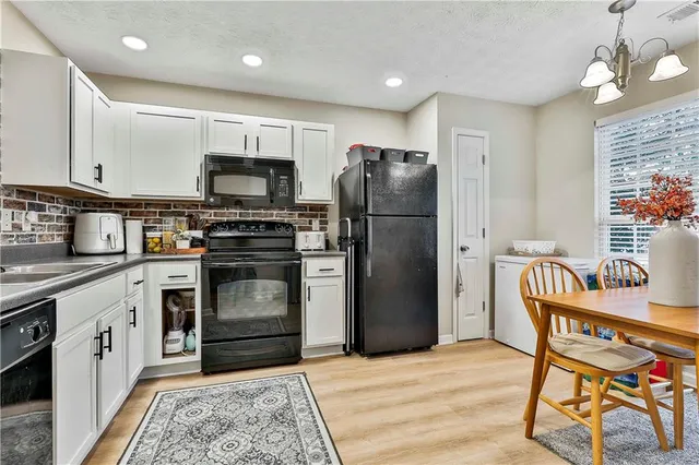 a kitchen with stainless steel appliances granite countertop a stove a refrigerator a kitchen island a dining table and chairs with wooden floor