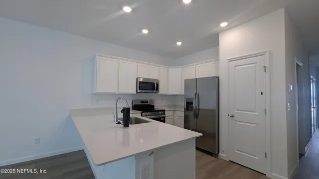 a kitchen that has a refrigerator a stove and white cabinets with wooden floor