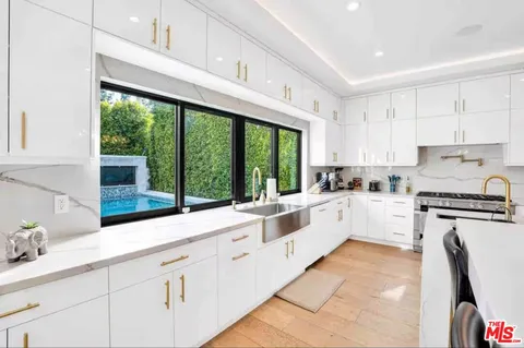 a kitchen with granite countertop white cabinets white appliances a large window and a counter space