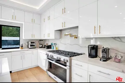 a kitchen with stainless steel appliances granite countertop a stove a sink and a white cabinets
