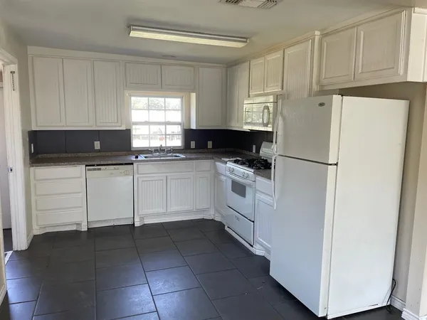 a kitchen with white cabinets and white appliances