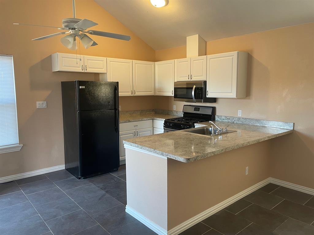 1610 Newsom Mound Road Springtown, TX 76082 - Photo 34 of 40 a kitchen with stainless steel appliances granite countertop a sink a refrigerator and a granite counter tops