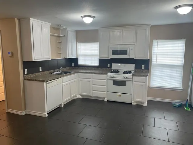 a kitchen with stainless steel appliances granite countertop white cabinets and window