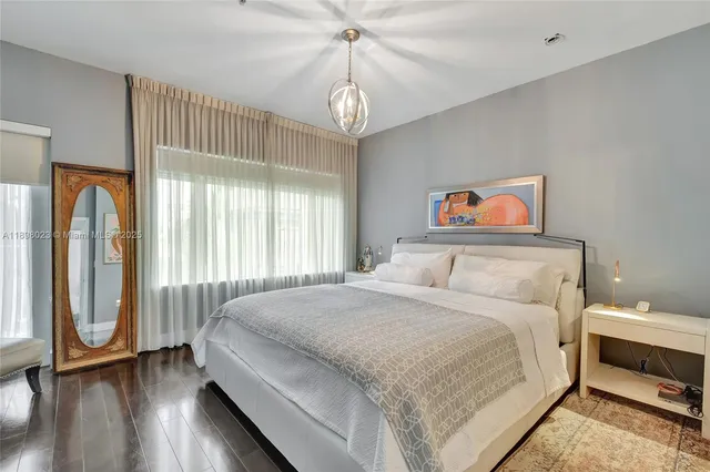 a spacious bedroom with a bed a dresser and a large window