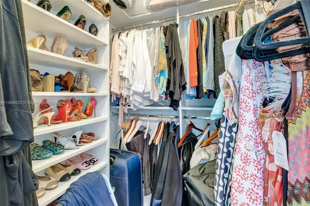 a view of walk in closet with clothes and shoes