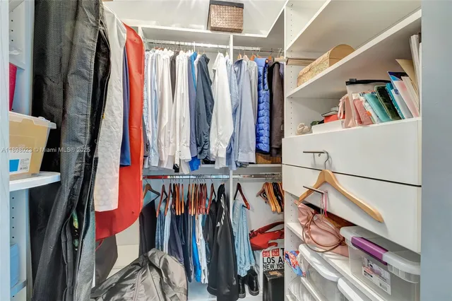 a view of walk in closet with clothes and shoes