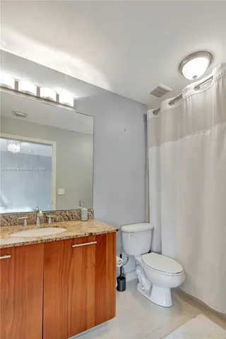 a bathroom with a granite countertop sink toilet and shower