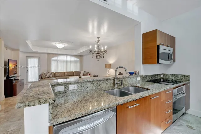 a kitchen with stainless steel appliances granite countertop a sink a stove top oven a counter space and cabinets
