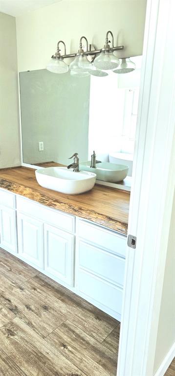 301 County Road Blossom, TX 75416 - Photo 14 of 19 Wood-finish flooring complementing a vanity with white cabinetry and a live-edge wood countertop