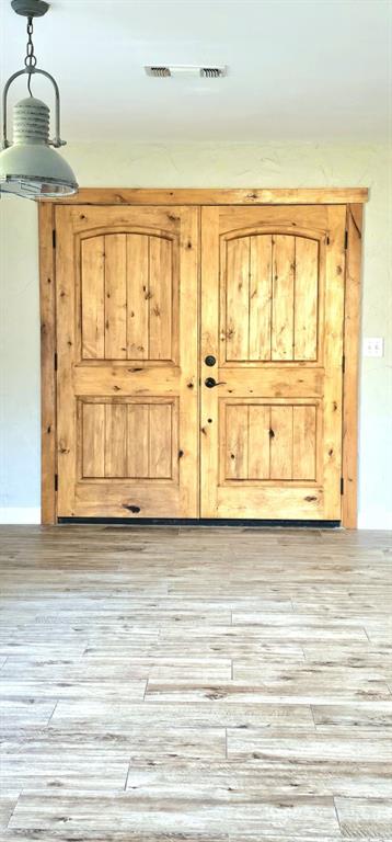 301 County Road Blossom, TX 75416 - Photo 17 of 19 Double rustic wood doors with arched paneling, dark hardware, and light wood-finish flooring