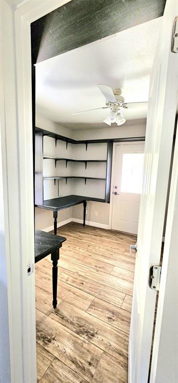 301 County Road Blossom, TX 75416 - Photo 19 of 19 Versatile interior room featuring wood-finish flooring, built-in shelving, integrated desk space, a ceiling fan with light fixture, and a white exterior door