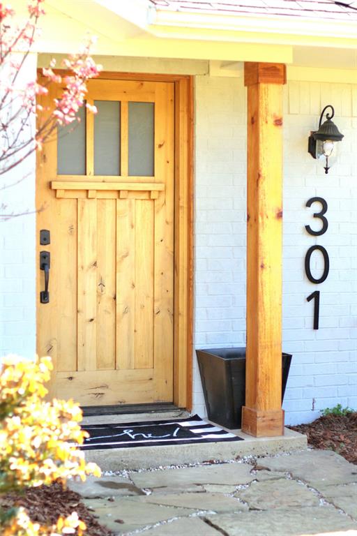 301 County Road Blossom, TX 75416 - Photo 3 of 19 Natural wood entry door with upper window panes, complemented by a substantial wood support post and white brick exterior