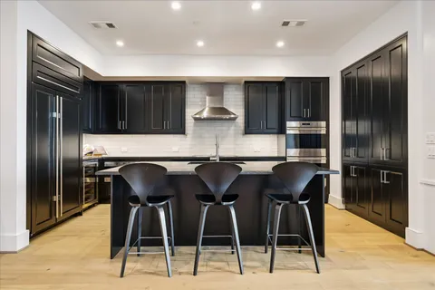 a kitchen with stainless steel appliances kitchen island granite countertop a refrigerator a stove a microwave and island with wooden floor