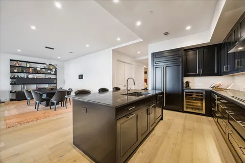 a kitchen with stainless steel appliances granite countertop a stove top oven a sink a dining table and chairs with wooden floor