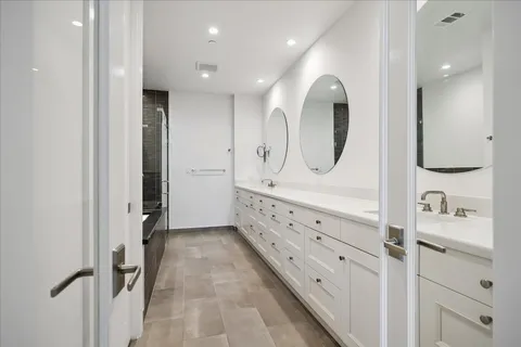 a bathroom with a double vanity sink mirror and shower