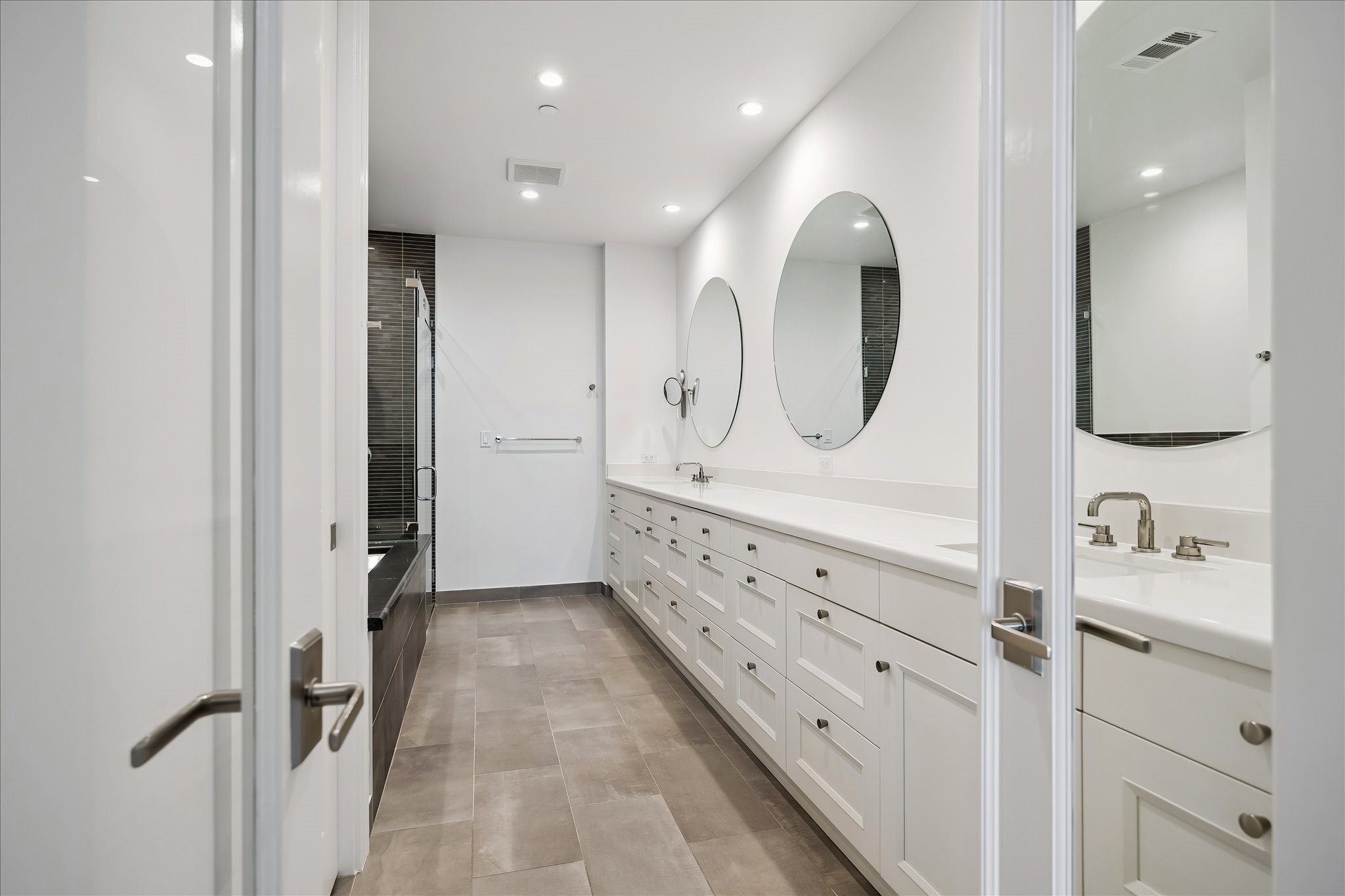2325 Welch Street, Unit 704 Houston, TX 77019 - Photo 25 of 33 A spa-like primary bath complete with dual vanities, a soaking tub, and a walk-in shower with tile surround. Clean finishes and ample storage create a serene, functional space.
