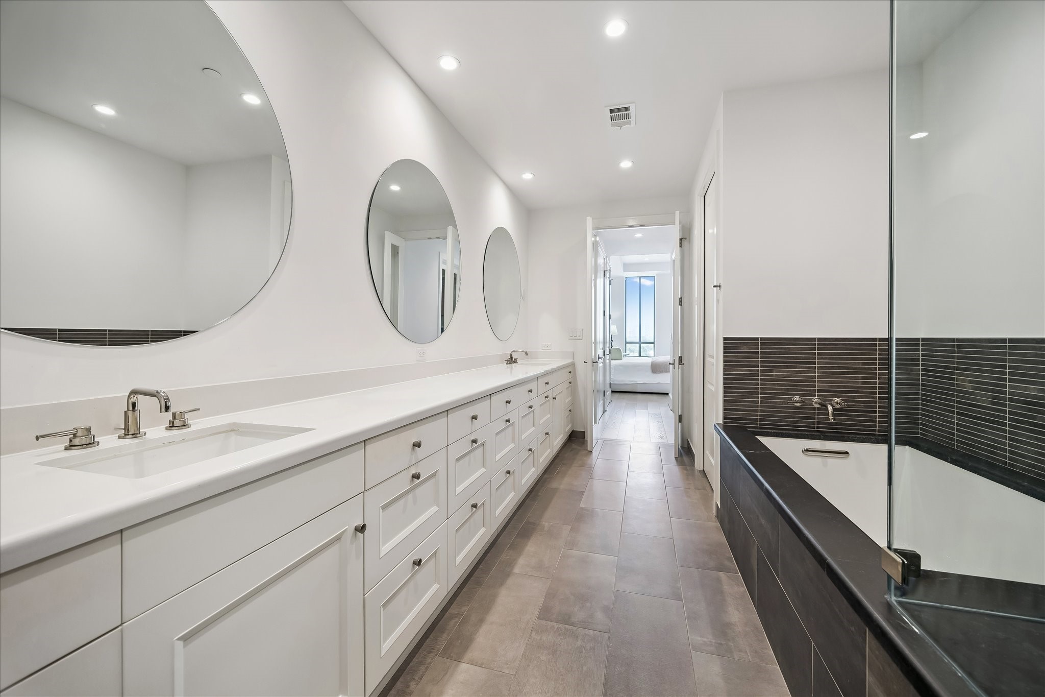 2325 Welch Street, Unit 704 Houston, TX 77019 - Photo 27 of 33 Thoughtfully designed with dual Kohler sinks, generous cabinetry, and three statement mirrors, this bathroom blends style and practicality. A soaking tub and separate shower enhance the everyday experience.