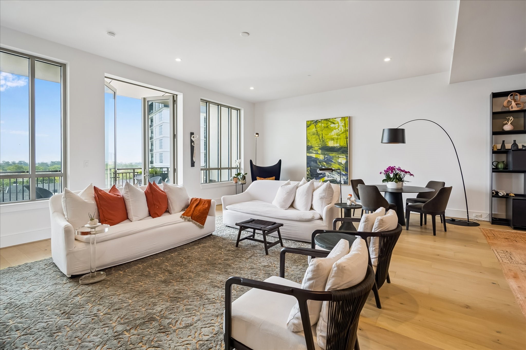 2325 Welch Street, Unit 704 Houston, TX 77019 - Photo 6 of 33 A spacious living room with 11’ ceilings, a striking stone-surround fireplace, and a wall of windows with northern exposure. The space opens effortlessly to the balcony for indoor-outdoor living.