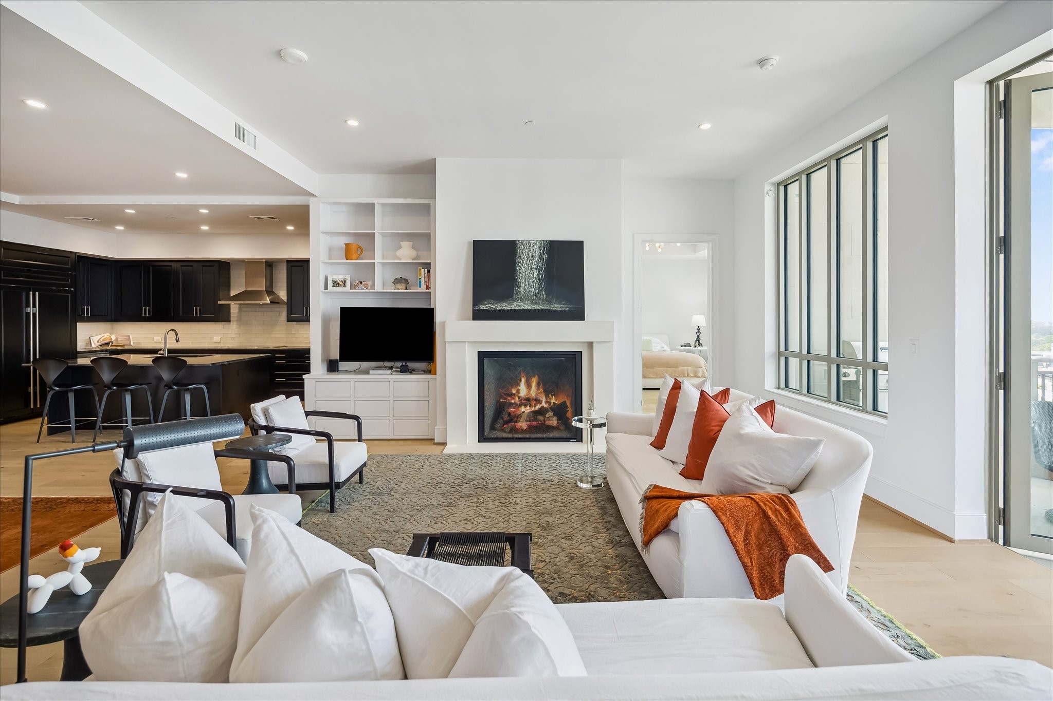 2325 Welch Street, Unit 704 Houston, TX 77019 - Photo 7 of 33 Generously scaled with 11’ ceilings and a full wall of north-facing windows, this living space feels both open and inviting. The stone-surround fireplace adds warmth and a refined focal point.