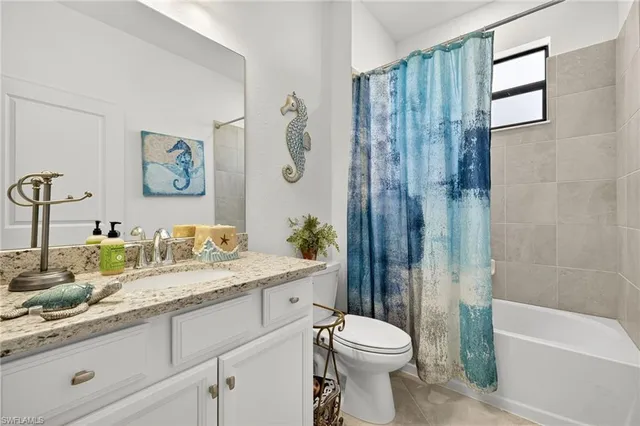 a bathroom with a granite countertop sink a toilet and shower