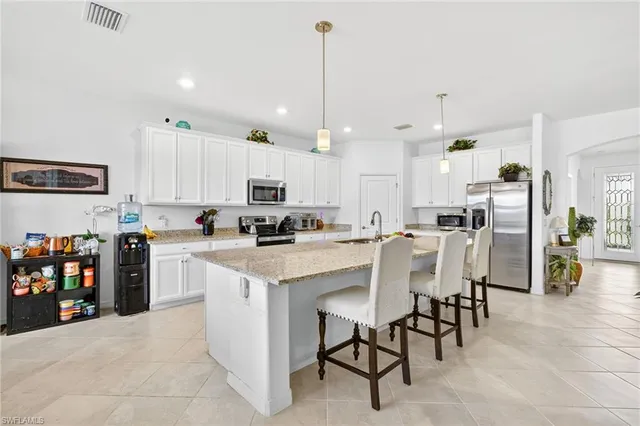a kitchen that has a lot of white cabinets and stainless steel appliances