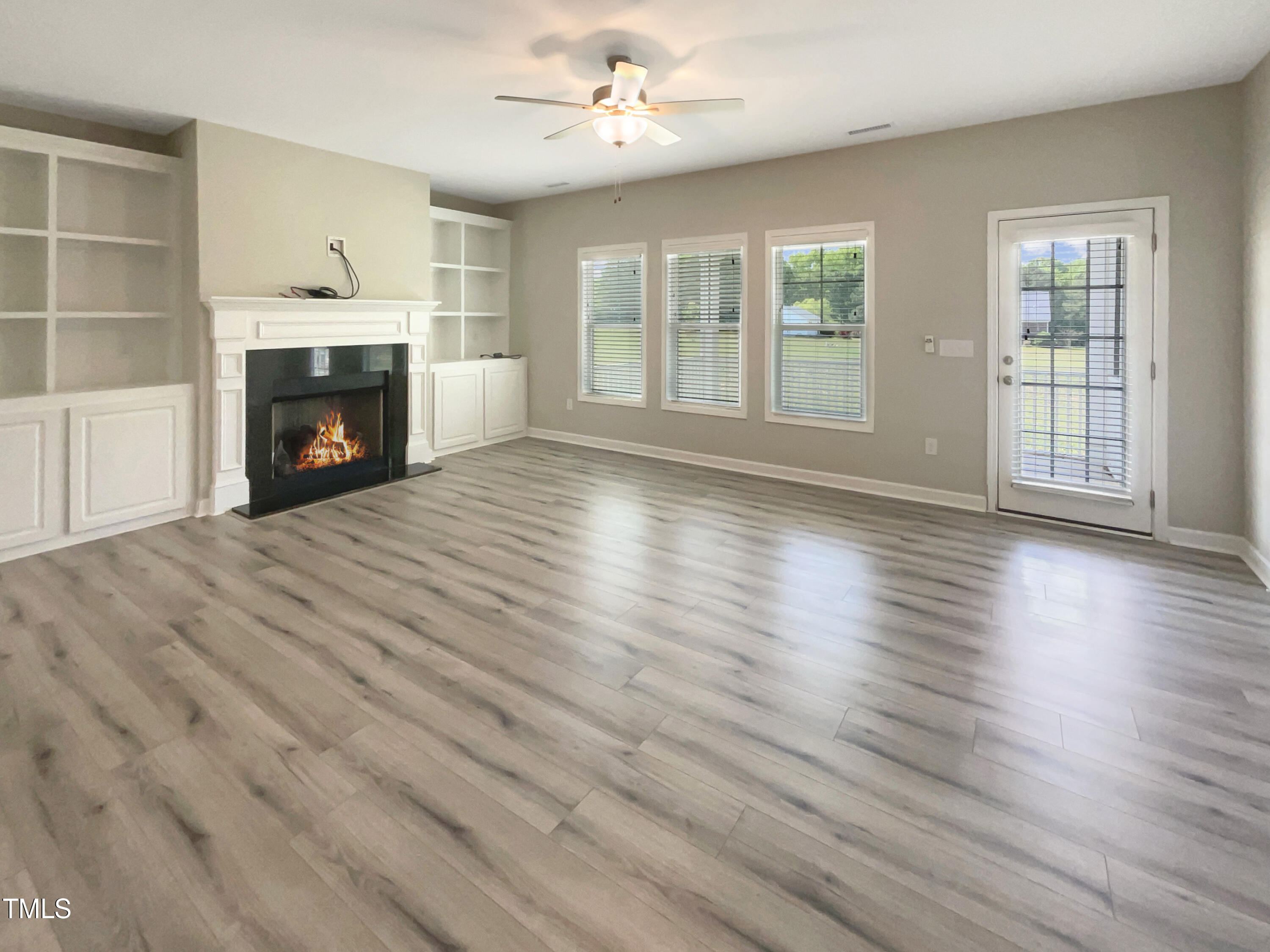 197 Steep Rock Drive Willow Spring, NC 27592 - Photo 3 of 20 an empty room with wooden floor fireplace and windows