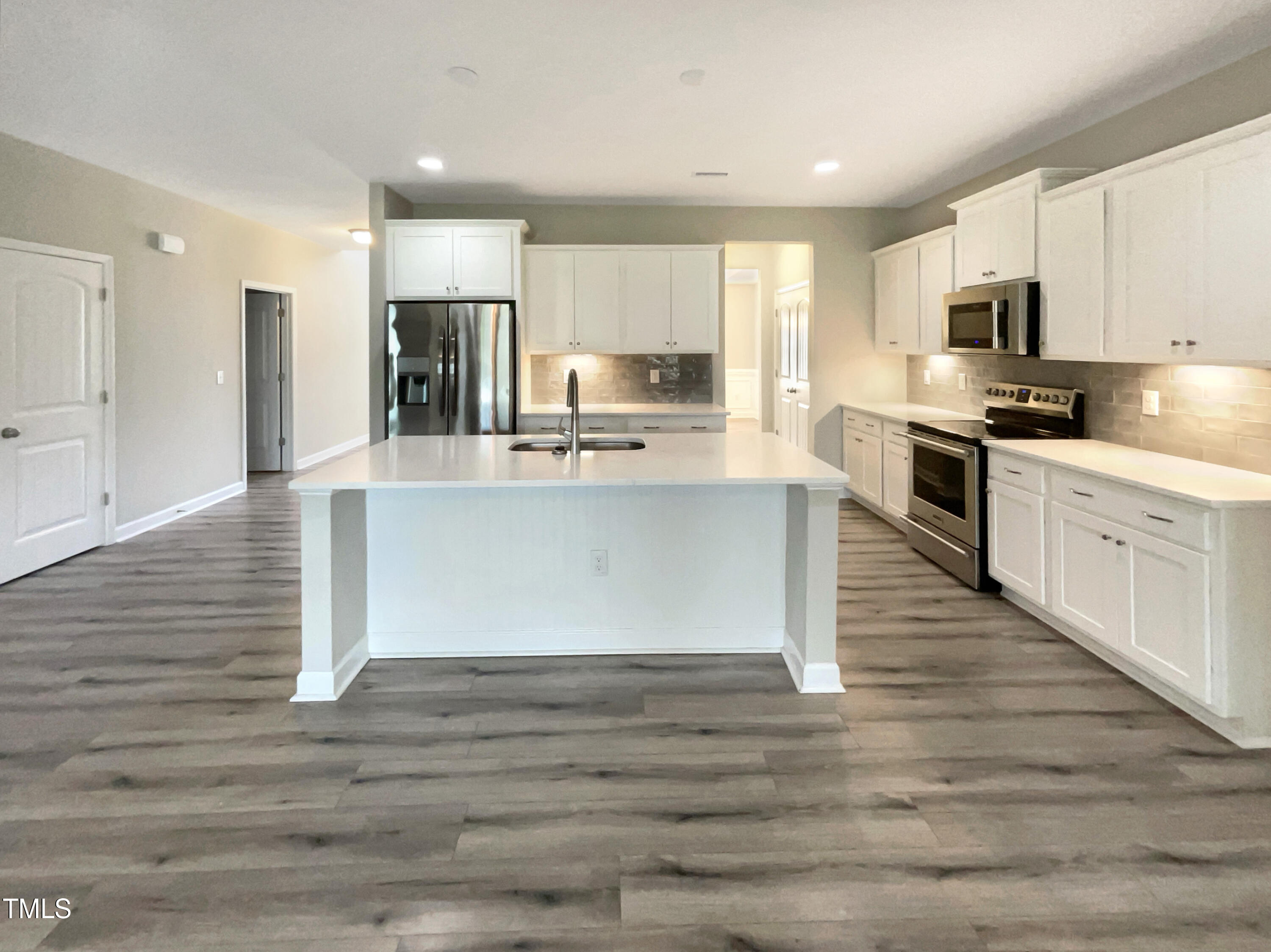 197 Steep Rock Drive Willow Spring, NC 27592 - Photo 6 of 20 a large kitchen with stainless steel appliances granite countertop a stove top oven a refrigerator white cabinets and wooden floor