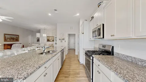 a large kitchen with stainless steel appliances granite countertop a lot of counter space and wooden floors