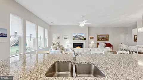 a kitchen with stainless steel appliances granite countertop a sink a stove counter space and living room view