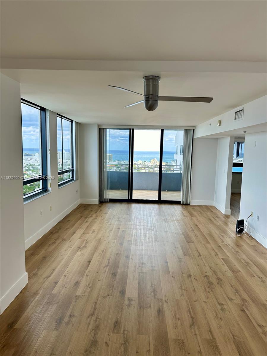 a view of empty room with wooden floor and fan