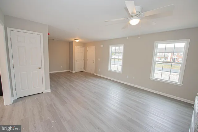 a open kitchen with stainless steel appliances granite countertop a refrigerator a sink dishwasher a stove and white cabinets with wooden floor