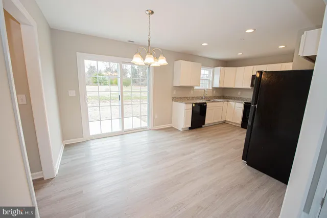 a kitchen with granite countertop white cabinets and black appliances