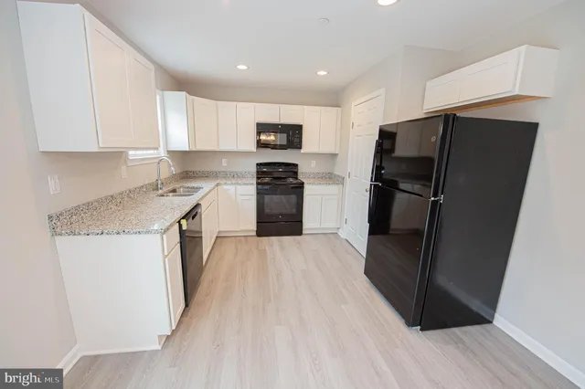 a kitchen with stainless steel appliances granite countertop a refrigerator a sink a stove and a refrigerator