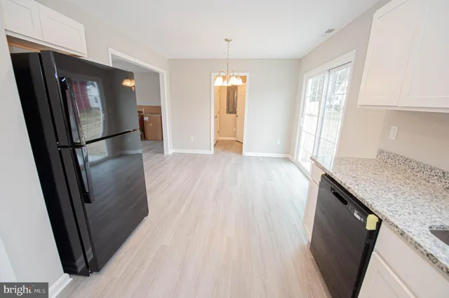 a kitchen with a refrigerator a stove top oven and white cabinets
