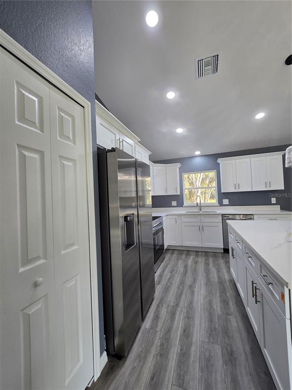245 Locust Pass Lane Ocala, FL 34472 - Photo 19 of 41 a kitchen with stainless steel appliances granite countertop a refrigerator a sink dishwasher a stove and white countertops with wooden floor