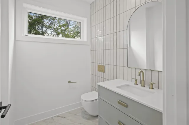 a bathroom with a granite countertop toilet a sink and a window