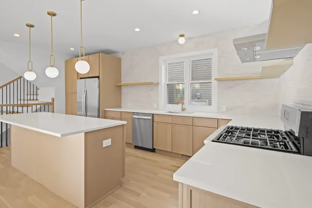 a kitchen that has a lot of white cabinets and stainless steel appliances