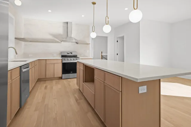 a kitchen with stainless steel appliances granite countertop a sink a stove and a refrigerator