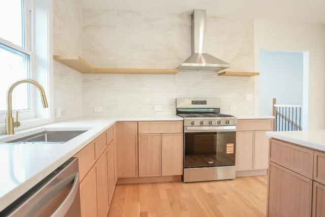 a kitchen with stainless steel appliances a stove a sink and a white cabinets with wooden floor