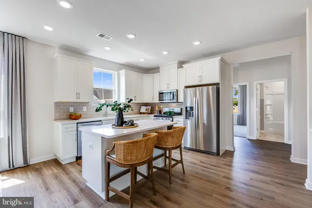 a kitchen with stainless steel appliances a refrigerator a stove a sink dishwasher and a refrigerator with wooden floor