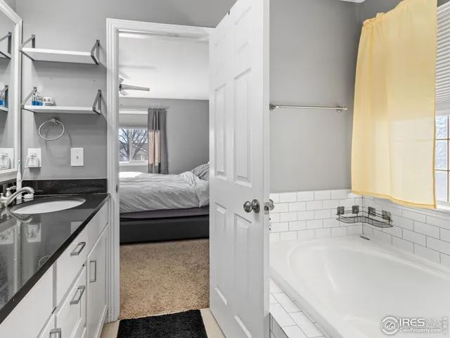 a en suite bathroom with a granite countertop sink and a tub