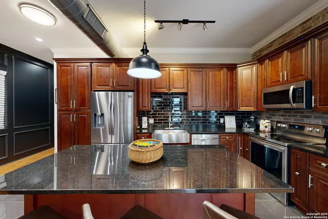a kitchen with stainless steel appliances granite countertop a refrigerator a stove a sink dishwasher a dining table and chairs with wooden floor