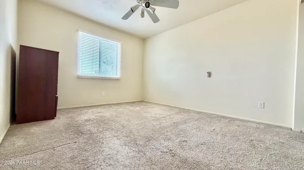 an empty room with a chandelier fan and windows