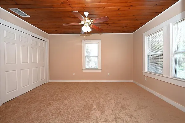 an empty room with chandelier fan and windows