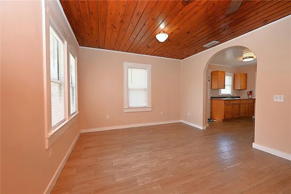 an empty room with wooden floor cabinet and windows