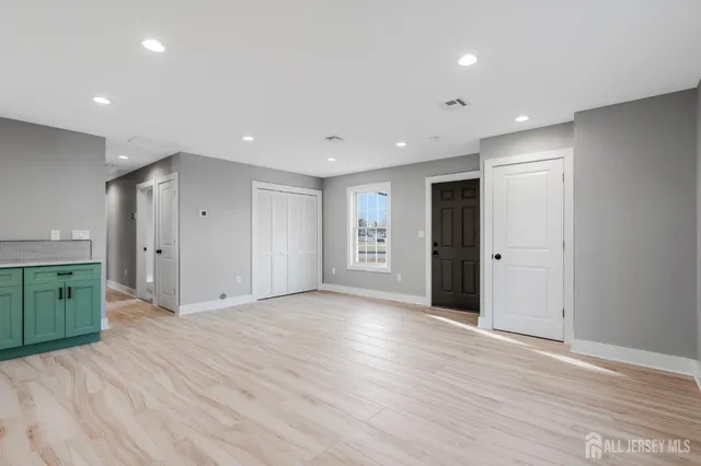 a view of an empty room with wooden floor and closet