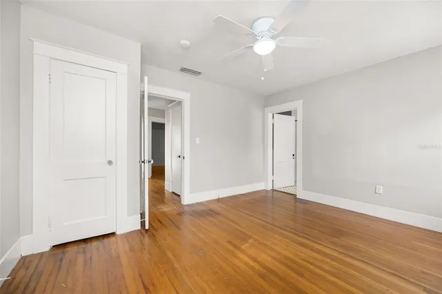 an empty room with wooden floor and a ceiling fan